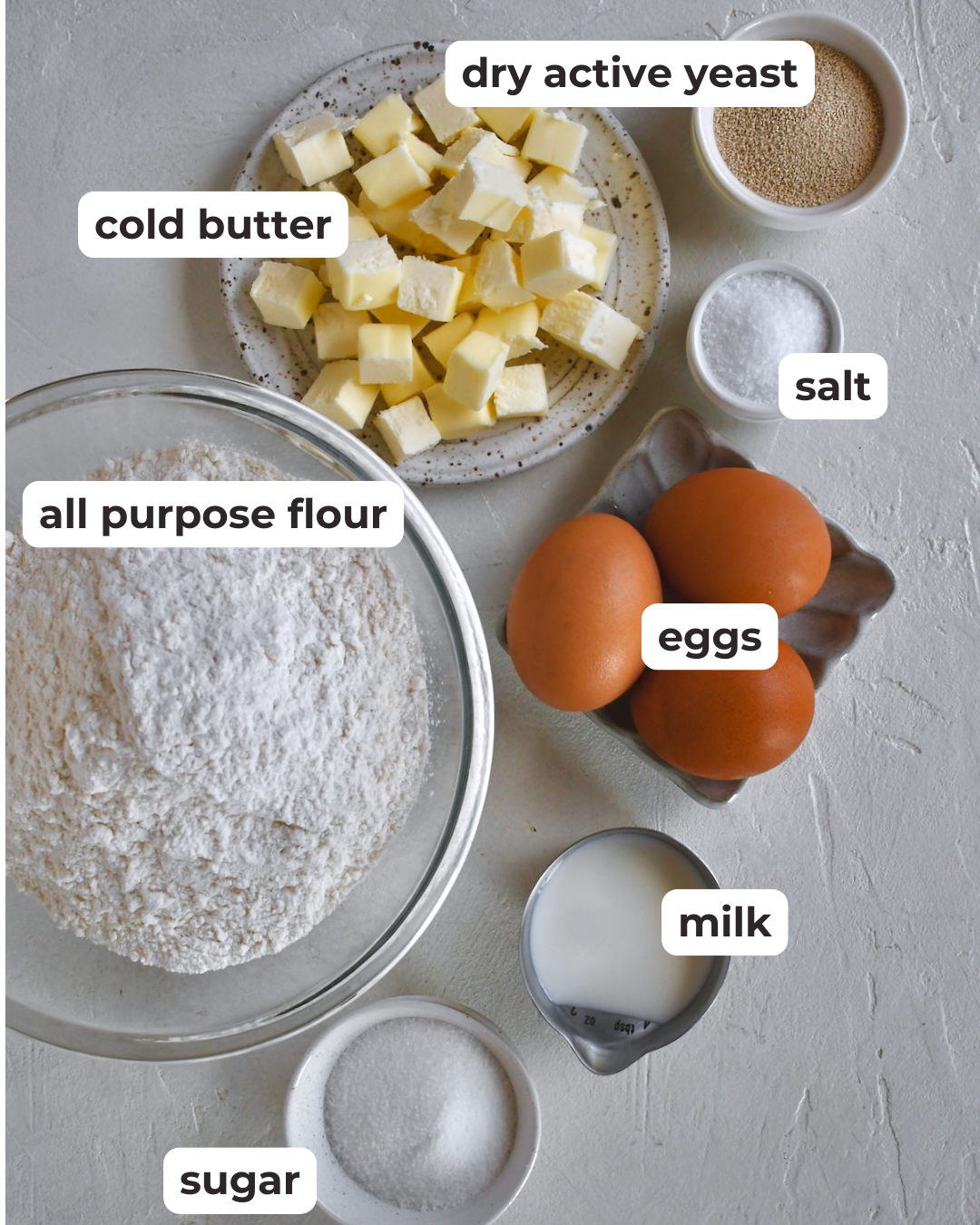 ingredients for homemade brioche bread including dry active yeast, cold butter, salt, all purpose flour, eggs, milk and sugar. 