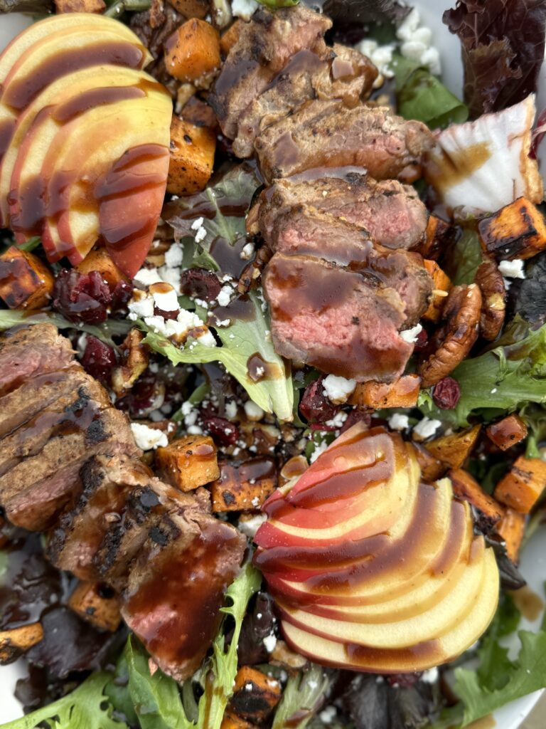 Steak Harvest Salad with sweet potato croutons, dried cranberries, crisp apples, feta cheese, and a homemade balsamic vinaigrette.